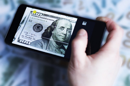 phone in hand, picture of dollar, on the background of dollars