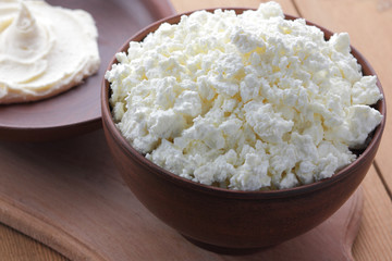 Cheese, cottage cheese and cream in clay ware, fresh curd on a wooden background, rustic sour cream, brown shade, healthy food, French breakfast, top view, goat curd, protein