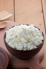 Cheese, cottage cheese and cream in clay ware, fresh curd on a wooden background, rustic sour cream, brown shade, healthy food, French breakfast, top view, goat curd, protein