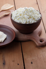 Cheese, cottage cheese and cream in clay ware, fresh curd on a wooden background, rustic sour cream, brown shade, healthy food, French breakfast, top view, goat curd, protein