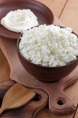 Cheese, cottage cheese and cream in clay ware, fresh curd on a wooden background, rustic sour cream, brown shade, healthy food, French breakfast, top view, goat curd, protein