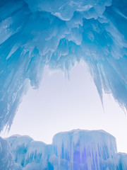 Winter ice castle caves with frozen icicles at sunset. - obrazy, fototapety, plakaty