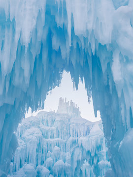 Winter ice castle caves with frozen icicles at sunset.