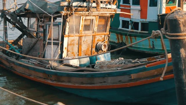 Old wooden half-ruined and wrecked ship is moored on a fishing dock