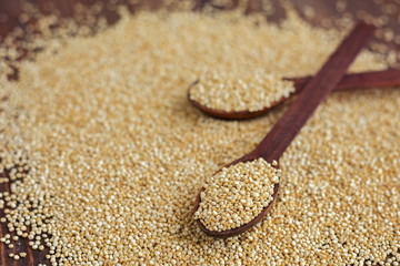 Kinoa seeds in wooden spoons on wooden table