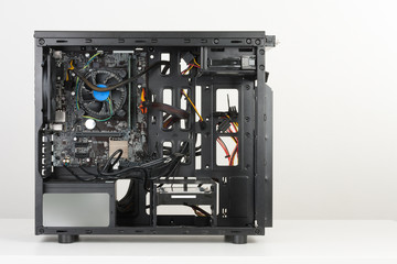 Building of PC, ATX motherboard inserted to black computer midi tower case.