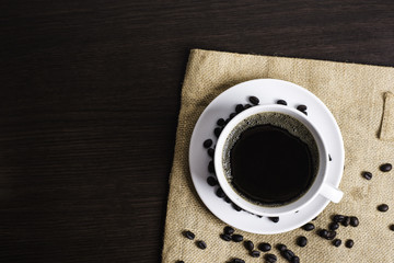 Black coffee in white cup and coffee bean on wood table background.