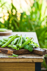 Green peas in pods on a wooden table