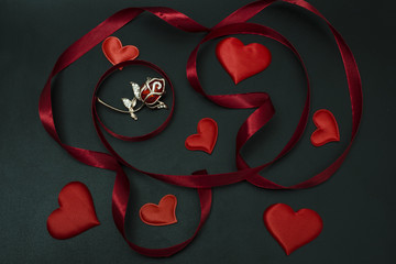Composition with brooch flower hearts and ribbon on a black background