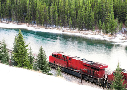 Red Train Traveling Along Railroad Track Through Winter Forest With Snow