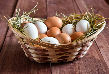 Different eggs white, brown in a basket on easter background of wooden boards