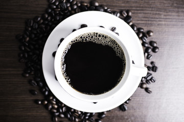 Black coffee in white cup and coffee bean on wood table background.