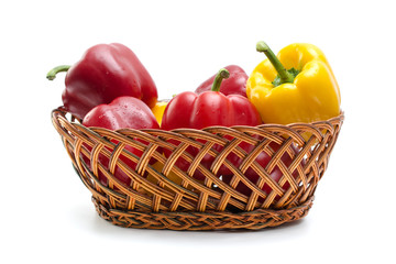bell peppers in a wicker basket isolated on white