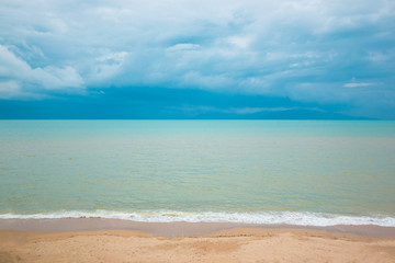 Fototapeta na wymiar Blue ocean and sand beach under cloudy sky in a bad weather