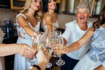 Newlyweds clang glasses with champagne with their family and friends