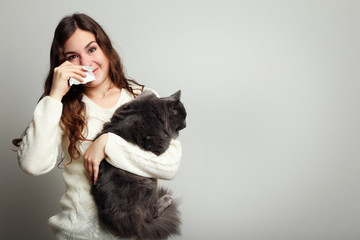 Young woman with allergy holding cat on grey background - obrazy, fototapety, plakaty