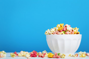 Colorful popcorn in bowl on blue background