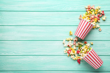 Obraz premium Słodki popcorn w pasiastych filiżankach na miętowym drewnianym stole