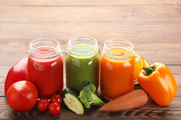 Vegetables smoothie in jars on wooden table