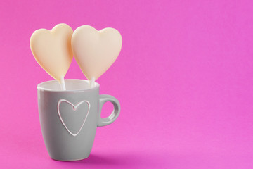Two white chocolate candy hearts on pink