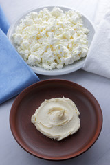 Obraz na płótnie Canvas Cheese, cottage cheese on a white plate, fresh cottage cheese on a white and blue napkin, dairy product on a white background, healthy food, French breakfast, top view, goat curd in minimalist style, 