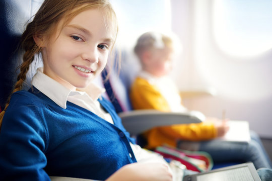 Adorable little girls traveling by an airplane. Child sitting by aircraft window and drawing a picture with colorful pencils.