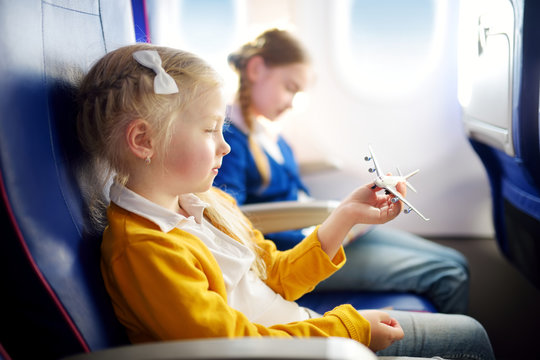 Adorable little girls traveling by an airplane. Child sitting by aircraft window and drawing a picture with colorful pencils.