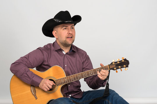 The man's portrait in a cowboy's black hat with guitar.