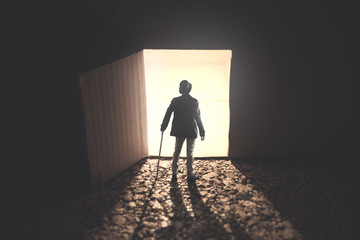 man standing in front an open lightened door in the dark