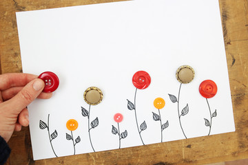 hand spreads flowers from buttons on a white background. children's background - obrazy, fototapety, plakaty