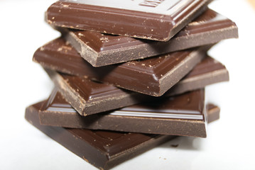 Pieces of dark chocolate on white background. Macro