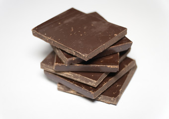 Pieces of dark chocolate on white background. Macro