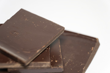Pieces of dark chocolate on white background. Macro