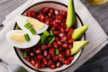 Home recipes: salad with avocado, eggs and pomegranate close-up, top view