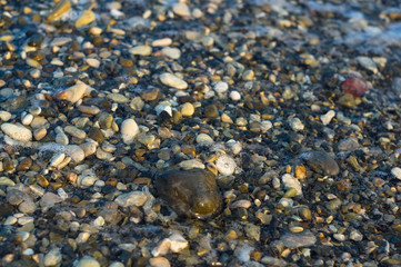 pebble stones on the sea beach, the rolling waves of the sea with foam