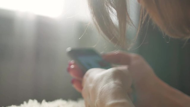 Young woman sitting on the bed and makes online shopping on a mobile phone. Online shopping concept.