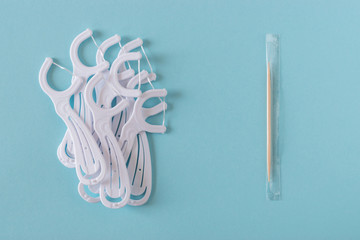 White dental flossers and toothpick on a bright blue background.