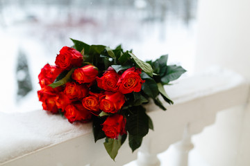 Bouquet of roses in the snow on a white railing. On the snow lay a bouquet of beautiful pink and white roses. The reference picture.