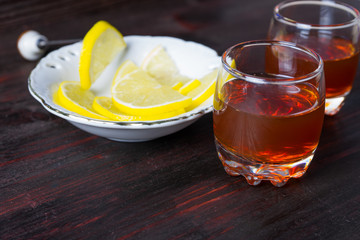 A glass of alcohol and sliced lemon.