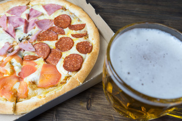 Light beer in glass and fragrant Italian pizza.