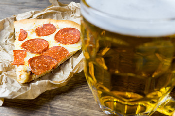 Light beer in glass and fragrant Italian pizza.