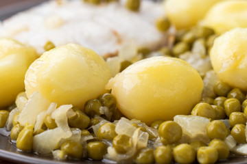 macro take of stewed potatoes in green sauce with peas, on wood