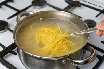 Spaghetti cooked in boiling water on a gas stove. The traditional Italian food.