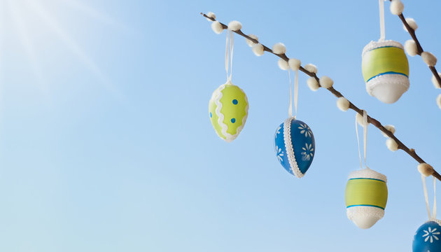 Osterstrauch Palmk&auml;tzchen mit bemalten Ostereier vor blauem Himmel und Sonne