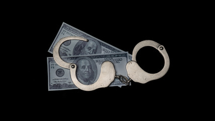 handcuffs and money. corruption. black background.