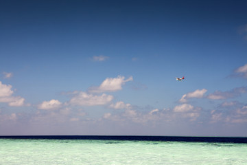 Small sea airplane flying above paradise tropical sea