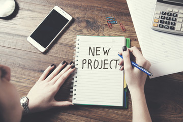 woman written new project  text on notepad with document on table