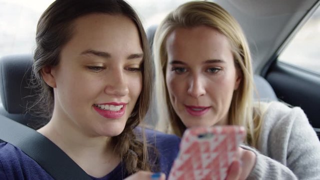 Happy Young Women Play On Smartphone Together In Back Seat Of Moving Car On Freeway - Shot On Red Scarlet-W Dragon In 4K/Slow Motion