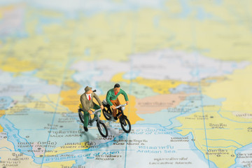 miniature people ride bicycle on a map for , travel around the world
