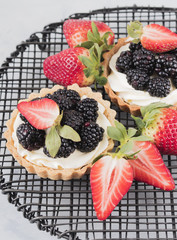 Berries creamy tarts served on grating plate